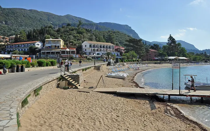 Beach and seafront promenade at Paleokastritsa with green hills behind