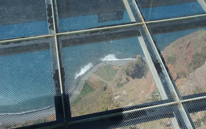 Looking through the glass floor of the Cabo Girão skywalk to the coast far below