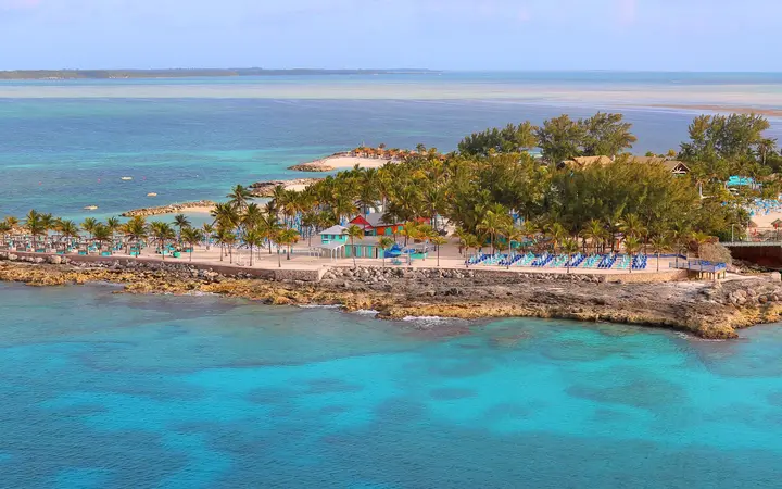 Palm-lined Chill Island at CocoCay with rows of blue loungers beside turquoise water