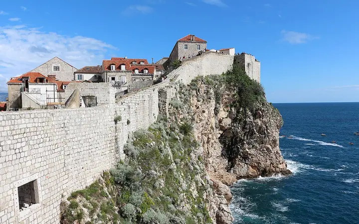 Dubrovnik's stone city walls running along a cliff above the Adriatic, with Old Town houses behind