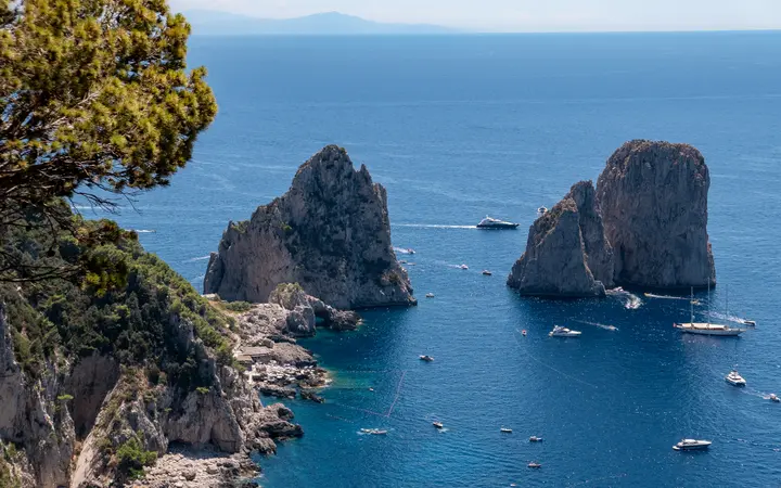 The Faraglioni rock stacks off Capri in a deep blue sea with boats