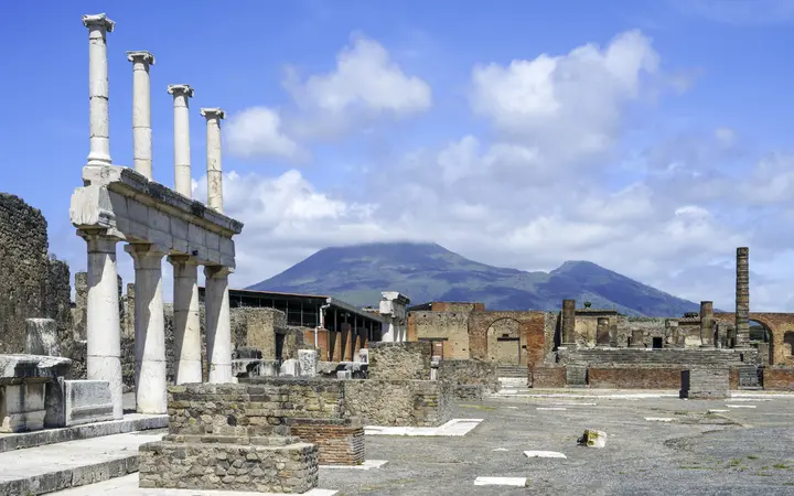 The Forum of Pompeii with columns in the foreground and Mount Vesuvius in the background