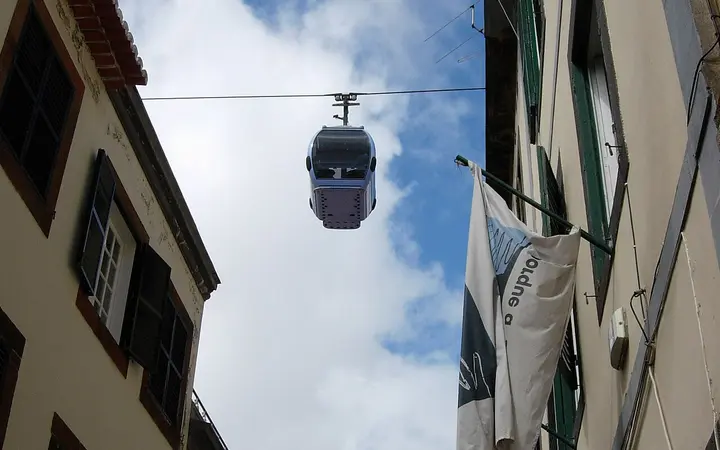 A Funchal–Monte cable car cabin passing above a narrow street in Funchal