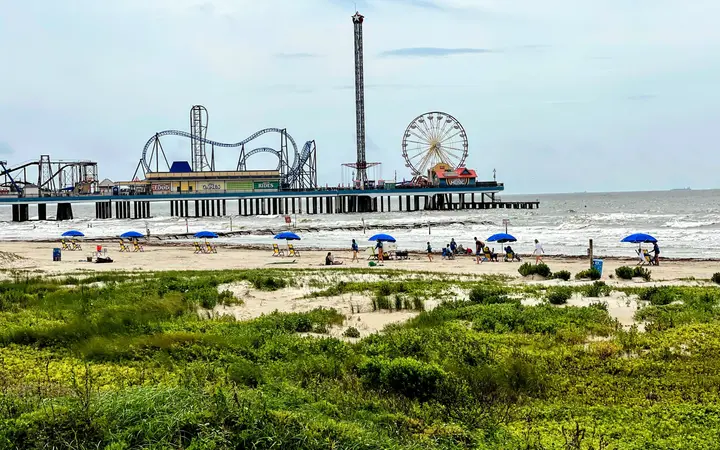 Galveston Island Historic Pleasure Pier with roller coaster and Ferris wheel above the beach
