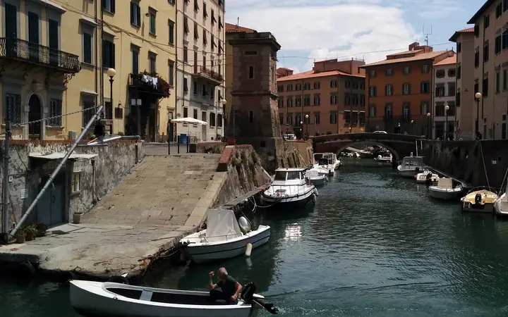 Canal lined with moored boats and pastel buildings in Livorno's Venezia quarter
