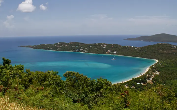 Aerial view of the curved white-sand beach and turquoise water of Magens Bay, St. Thomas