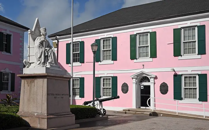 The pink House of Assembly with green shutters and the statue of Queen Victoria on Parliament Square, Nassau