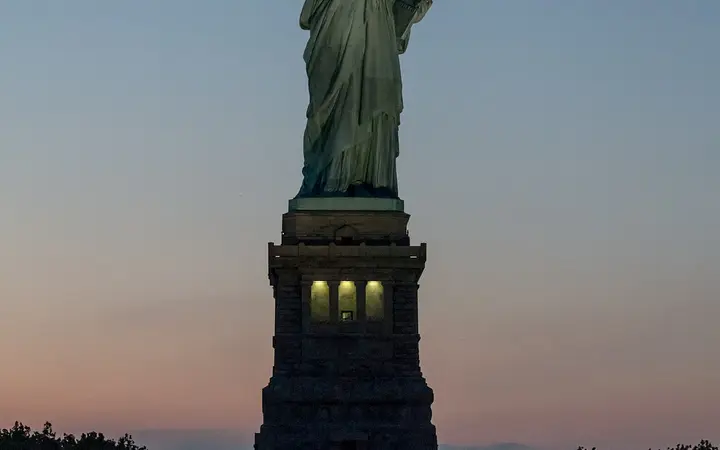 The Statue of Liberty on Liberty Island lit at dusk