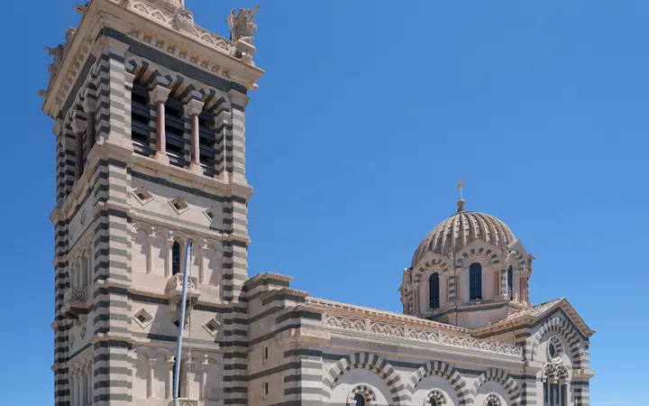 The bell tower and dome of Notre-Dame de la Garde basilica in Marseille under a blue sky