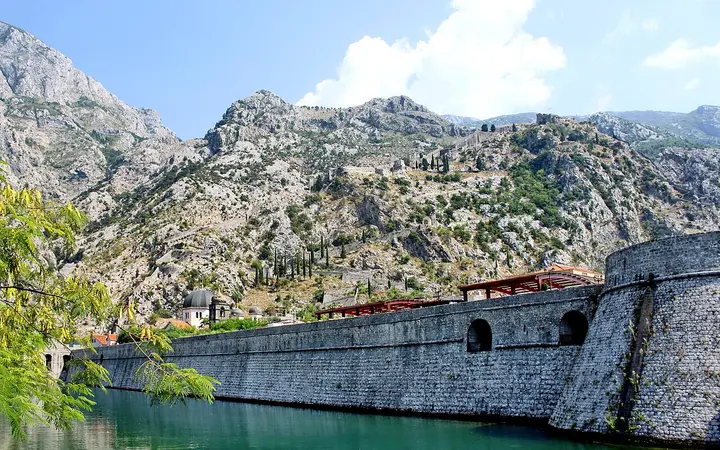 Kotor's northern city walls above the Škurda river, with the fortification line climbing the mountain behind