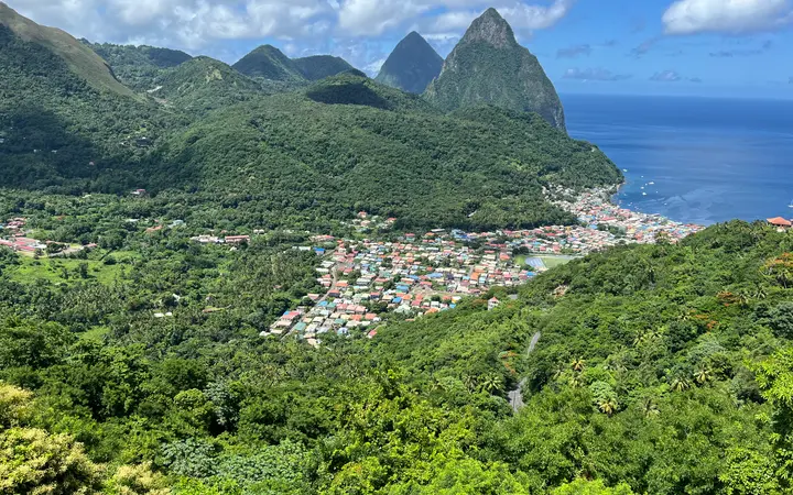 Soufriere town on the coast below the two Pitons peaks and green rainforest hills, Saint Lucia