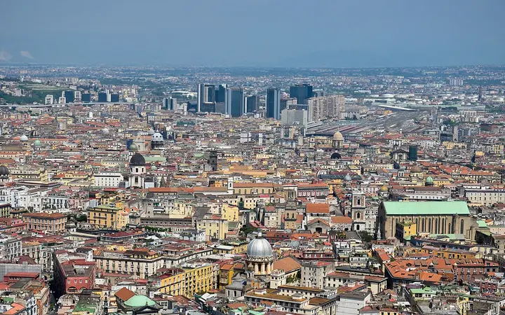 Rooftops and domes of the historic centre of Naples seen from above, with the Centro Direzionale towers in the distance