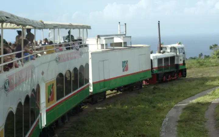 St. Kitts Scenic Railway train with passengers on the open upper deck, sea in the background