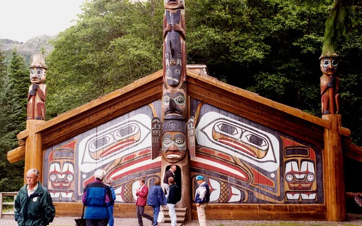 Painted Tlingit clan house with carved totem poles at Totem Bight State Historical Park