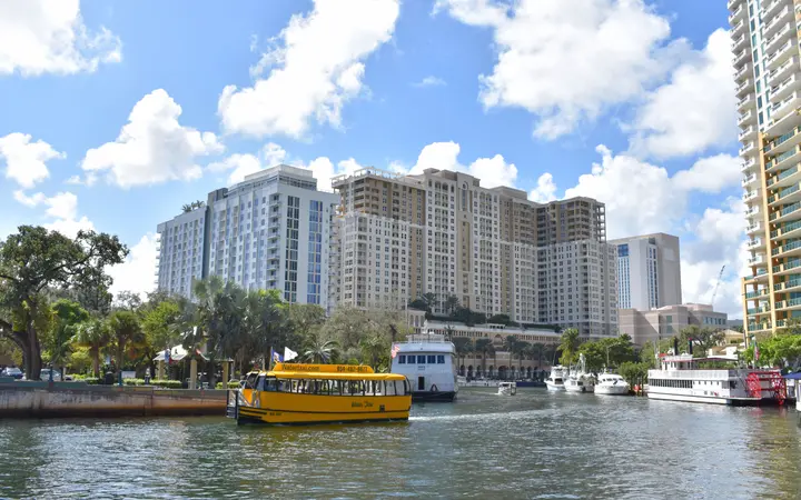 A yellow Water Taxi boat on the river below downtown Fort Lauderdale high-rises
