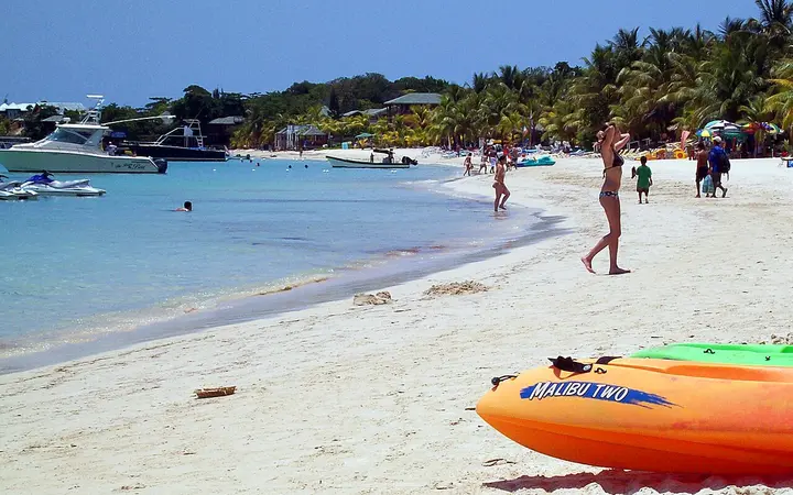 Sunbathers and kayaks on the white sand of West Bay Beach, Roatan