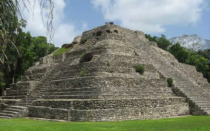Stepped Maya stone pyramid at the Chacchoben archaeological zone surrounded by jungle and lawn
