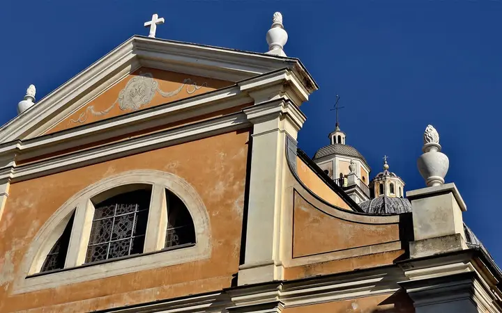 Ochre baroque façade and domes of Santa Maria Assunta Cathedral in Ajaccio against a deep blue sky