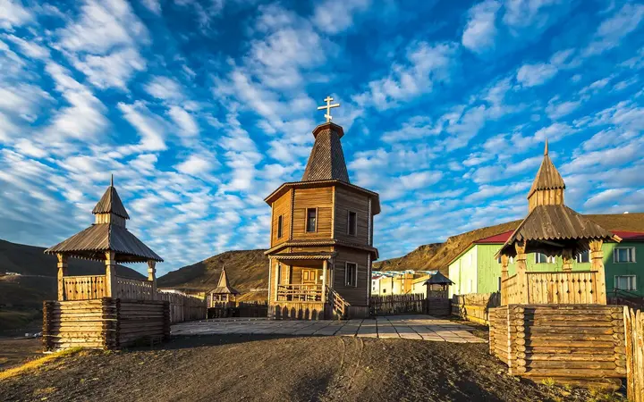 Wooden chapel with bell towers in Barentsburg under a blue sky