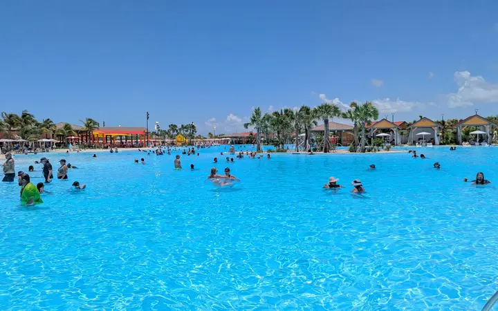 The large turquoise Calypso Lagoon pool, lined with palms and buildings, at Celebration Key