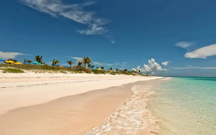 Wide white-sand Family Beach with turquoise water and palm trees at Disney Lookout Cay, Eleuthera