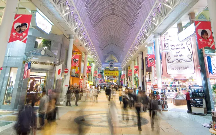 The arched glass-roofed Tenmonkan shopping arcade lined with shops in Kagoshima.