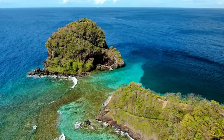 Aerial view of the forested volcanic rock of Fort Duvernette in turquoise water off Villa, St Vincent