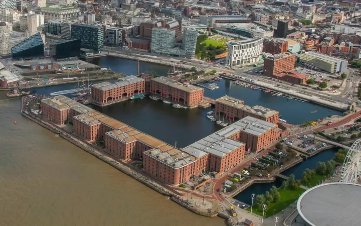 Aerial view of the Royal Albert Dock's red-brick warehouses around the dock basin beside the River Mersey in sunshine