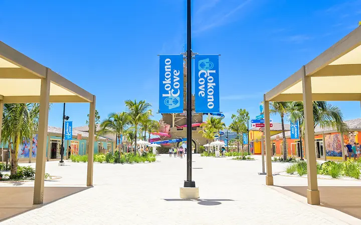 Shaded white walkway with blue Lokono Cove banners at the Celebration Key shopping village