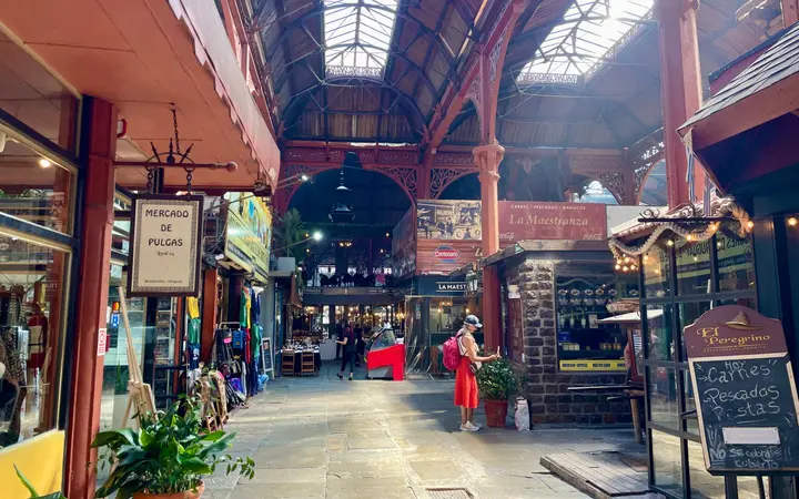 The iron-and-glass roofed hall of the Mercado del Puerto in Montevideo, with grill restaurants and shops along a stone walkway