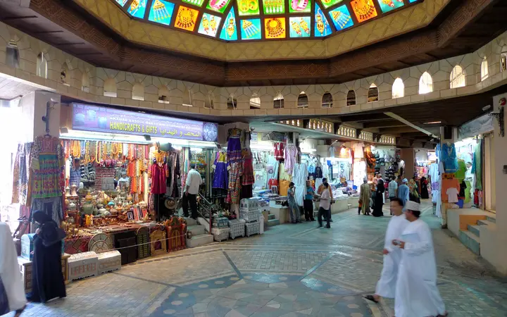 Entrance hall of Muttrah Souq with a stained-glass dome and shops.