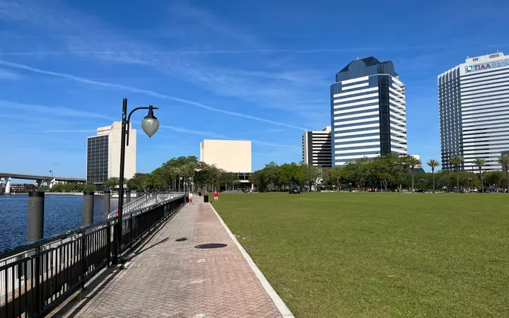 Riverside walkway and lawn along the St. Johns River with the downtown Jacksonville skyline