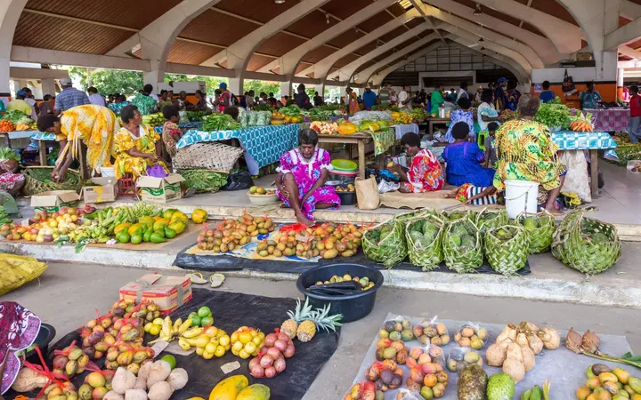 Tables of tropical fruit and vegetables under the roof of the Port Vila Central Market, Efate