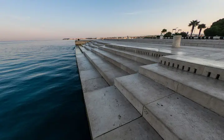 White marble steps of the Sea Organ descending into the calm sea on the Zadar waterfront at dusk